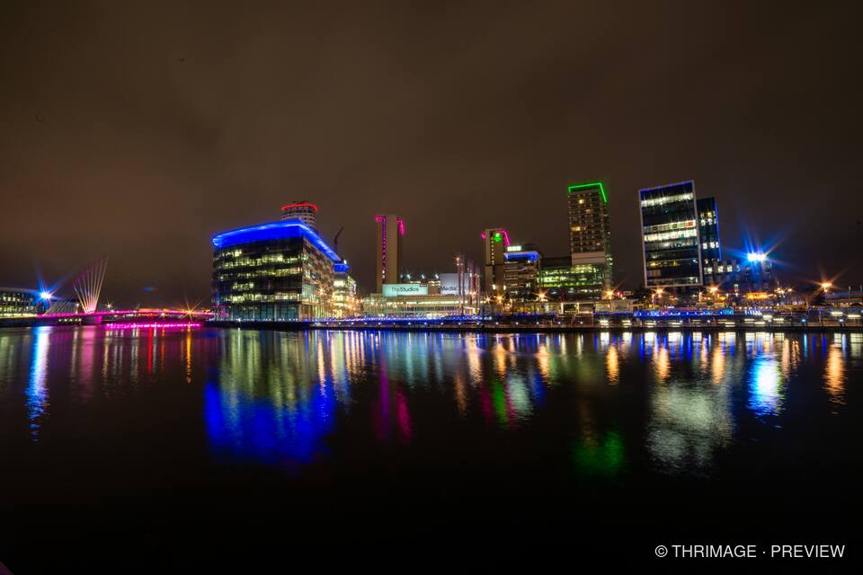 Illuminated MediaCity skyline reflected in Salford Quays at night