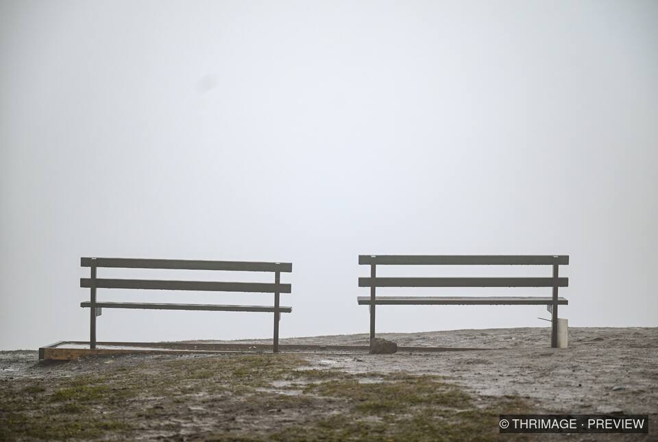 Two empty benches fading into dense mist