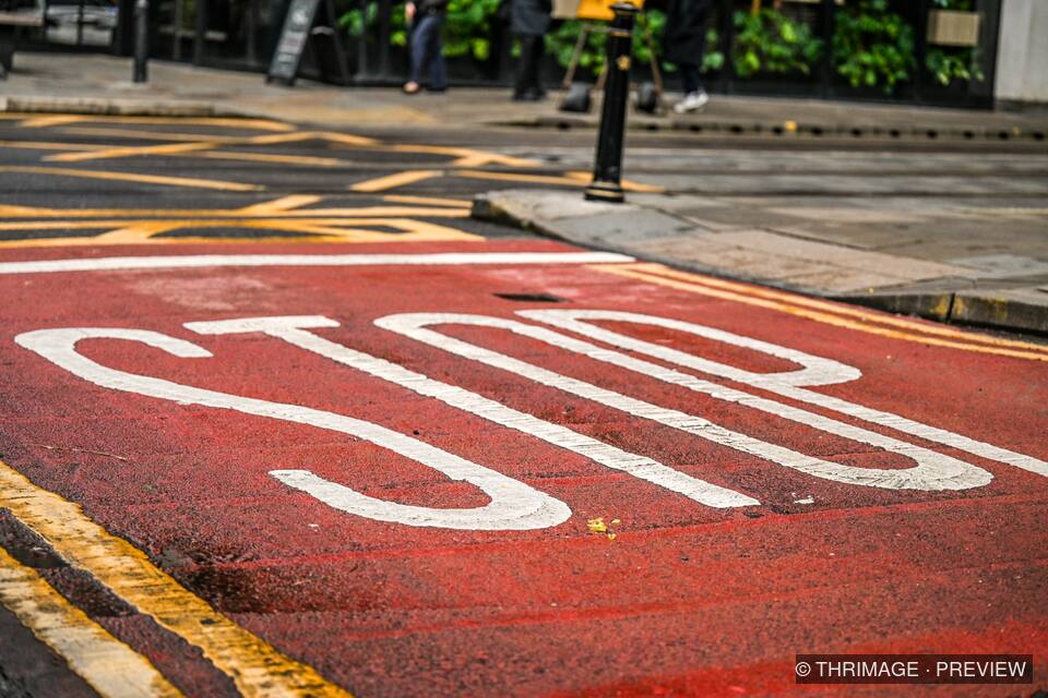 Large white STOP road marking on a red road surface
