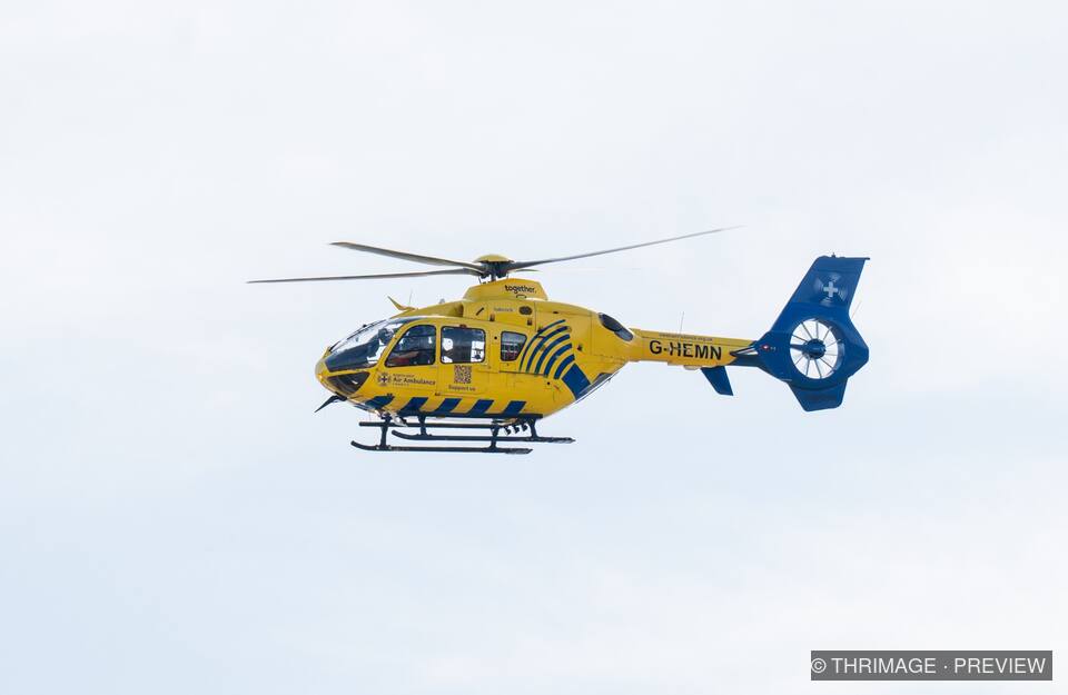 North West Air Ambulance helicopter flying against a pale sky