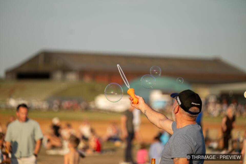 Man waving a bubble wand among floating soap bubbles