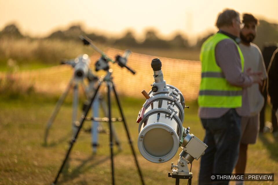 Telescope equipment arranged at a golden-hour astronomy event
