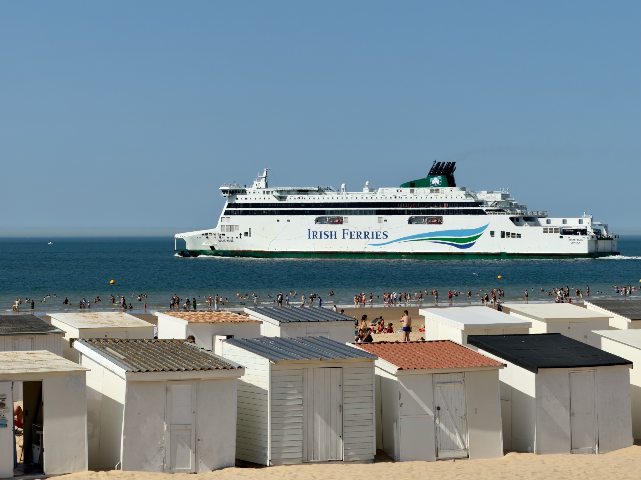 Irish Ferries passenger ship passing a busy beach lined with white huts