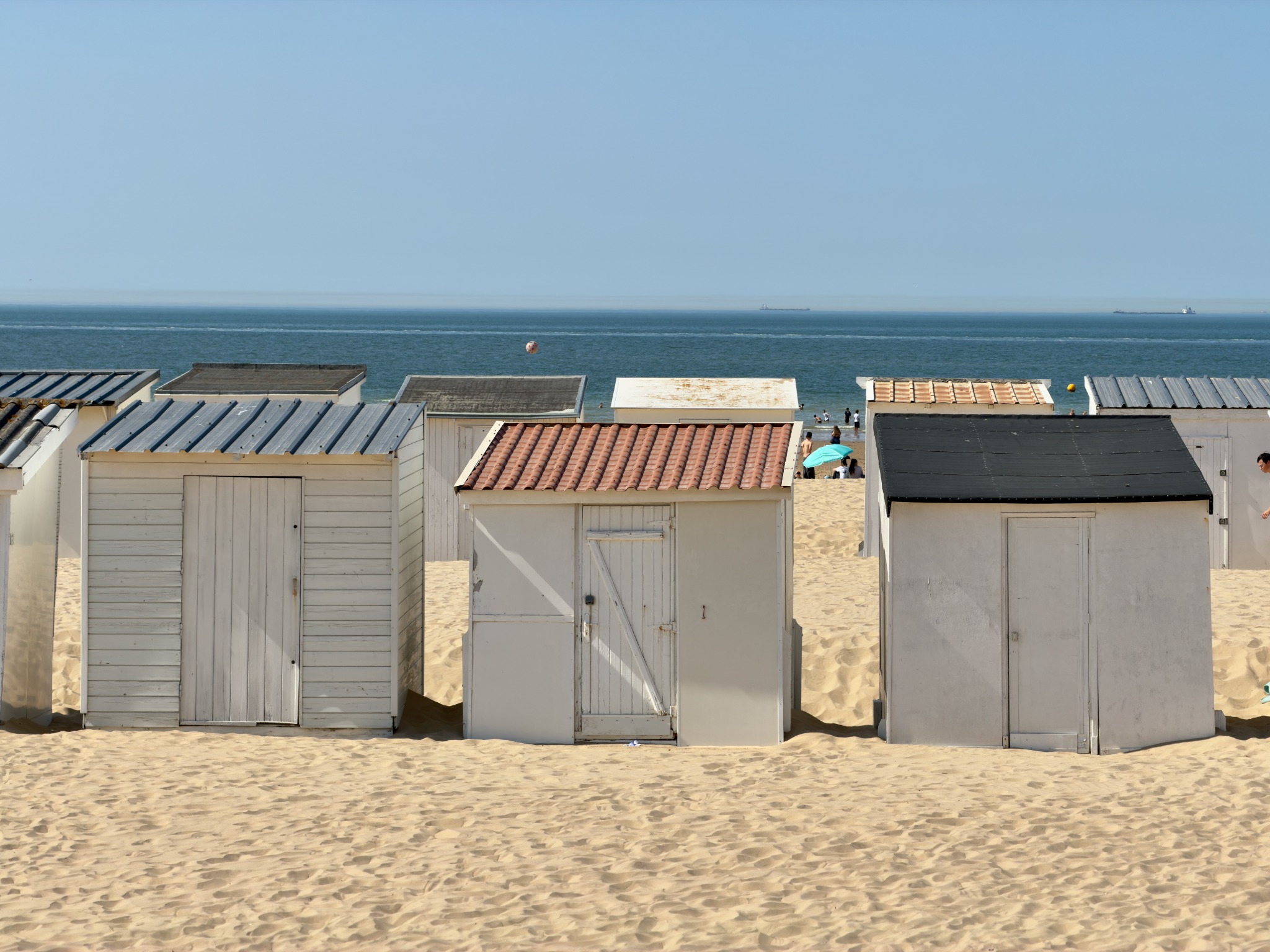 Rows of white beach huts facing a calm blue sea