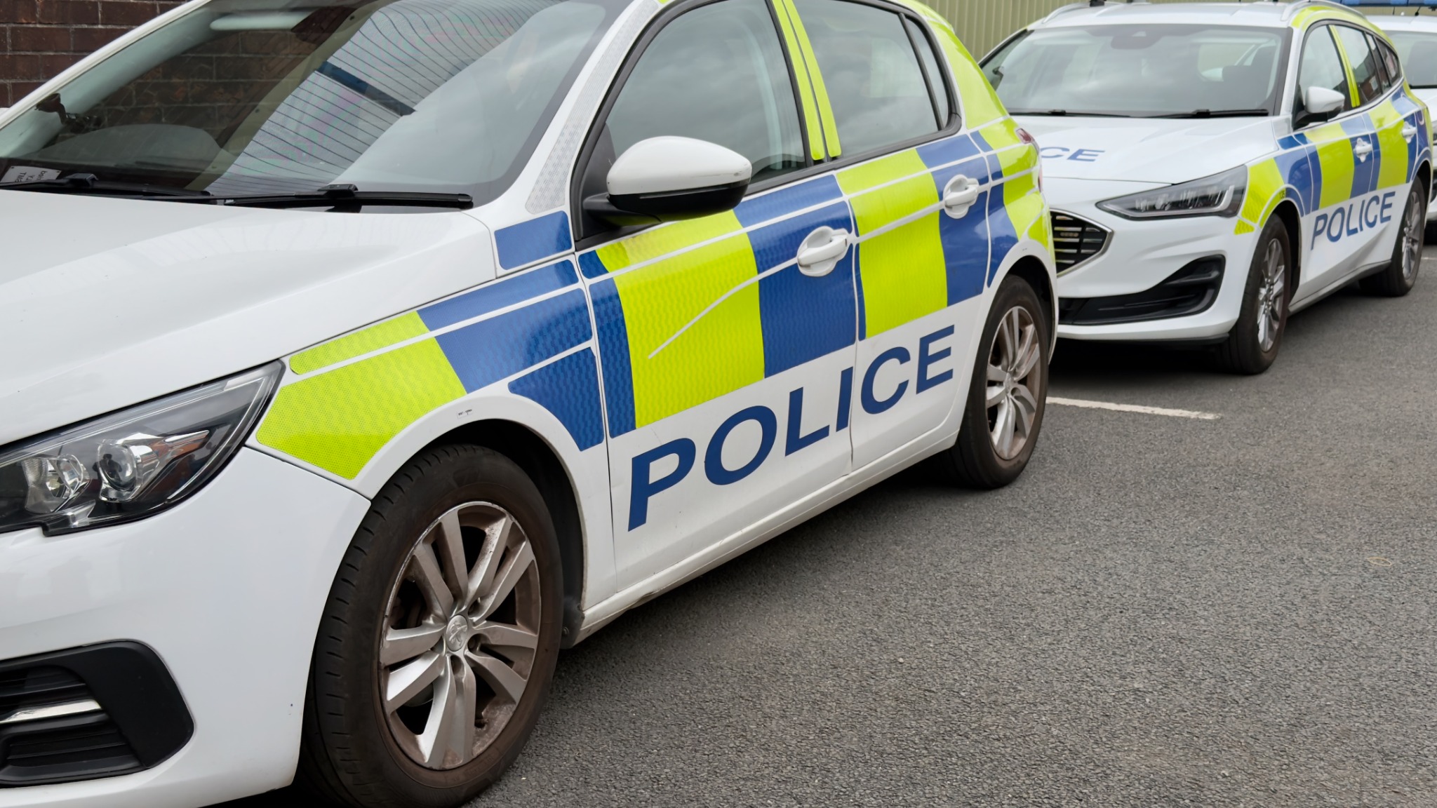 Two marked British police cars parked in line