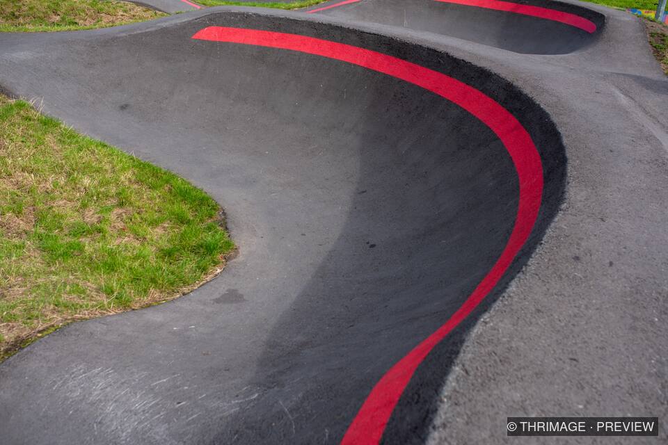 Black asphalt pump track with a sweeping red line